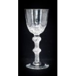 An 18th century balustroid wine glass, circa 1750, the optic moulded round funnel bowl, with