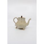 An early 18th Century Creamware tea-pot standing on 3 lions paw feet. Remnants of collectors label