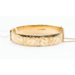 A 9ct gold hinged bangle, foliate engraved decoration, total gross weight approx 38.