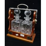 A Victorian style white metal mounted tantalus with a pair of decanters