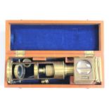 A boxed brass monocular microscope and accessories