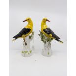 A pair of Meissen golden Orioles on tree stump supports, mid 20th Century crossed swords,