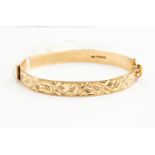 A 9ct gold bangle, foliate engraved decoration,