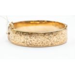 A 9ct gold bangle, Chester 1960, floral and scroll pattern front, approx 18.