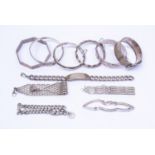 A collection of seven silver bangles including buckle, bamboo,