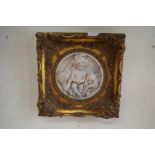 A pair of 19th Century style reconstituted wall plaques, carved in high relief with putti,