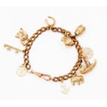 A gold plated charm bracelet containing eleven 9ct gold and yellow metal assorted charms,