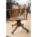 An oak swivel/rocker chair, studded leatherette seat, single column four balance legs,