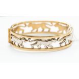 A 9ct gold two tone open bangle with white gold inset panthers, hinged,