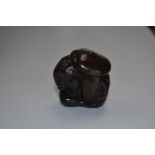 A treen netsuke in the form of a monkey sheltering under a large mushroo,
