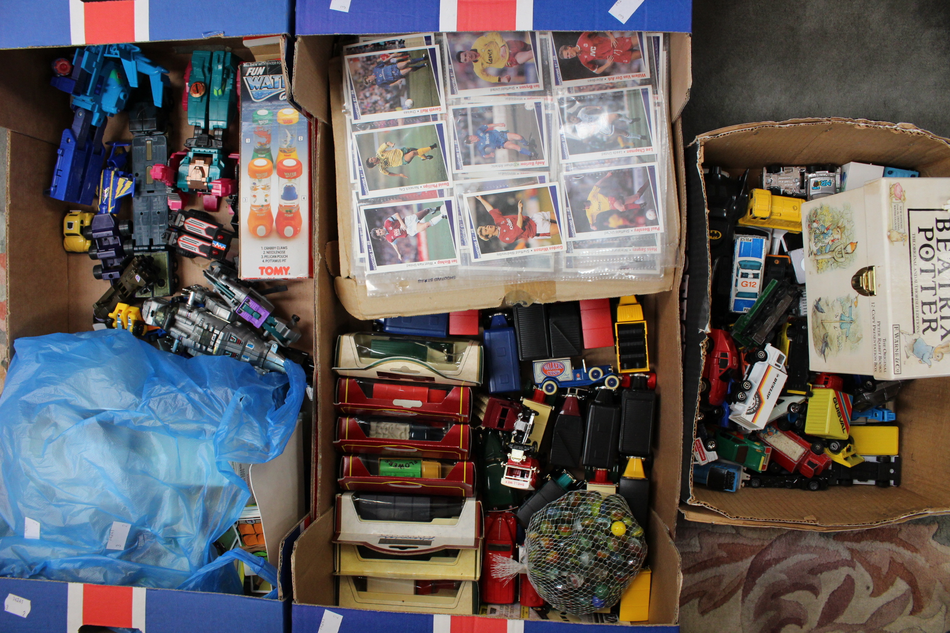 Two boxes of assorted diecast vehicles and Beatrix Potter books and cigarette cards