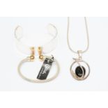 A modern silver chain with pendant set with black stone; two silver bangles,