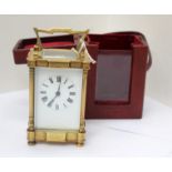 A brass carriage clock with white enamel dial, Roman numerals,