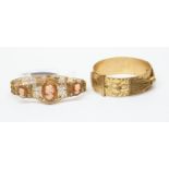 Two bracelets comprising a belt style cuff bangle and a cameo set yellow metal bracelet
