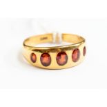 An 18ct gold and garnet dress ring, set with five graduated garnets, size M½,