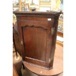 A George III oak wall hanging corner cupboard, brass H hinges,