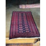 A small hand knotted woollen rug, with a red geometric pattern, blue ground, fringe to edge, 94cm