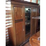 An Edwardian mahogany triple sectioned wardrobe, inlaid with stringing, the centre panel fitted with