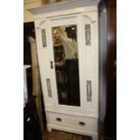 An Edwardian Art Nouveau white painted single door wardrobe, with a drawer to base