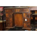 A Georgian style leather inset kneehole desk, fitted with eight drawers and a central cupboard,