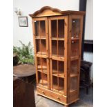 A contemporary pine two door glazed bookcase, the doors enclosing three shelves and a drawer to