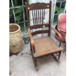 An Early 20th Century American style Oak spindle back rocking chair, cane work inlaid seating area