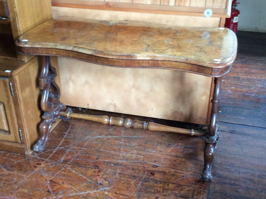 A mid Victorian walnut quarter veneered side table, of serpentine form, shaped supports, united by a