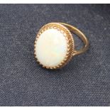 A 9ct yellow gold and opal ring, set oval cabochon precious white opal within wire work border,