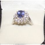 An 18ct. white gold, tanzanite and diamond cluster ring, claw set oval brilliant cut tanzanite to