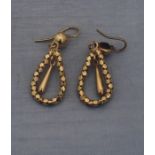 A pair of precious yellow metal drop earrings, having faceted tear drop shaped hinged hoop