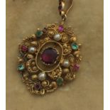 A precious yellow metal, ruby and emerald pendant, the filigree mount set central ovoid ruby with