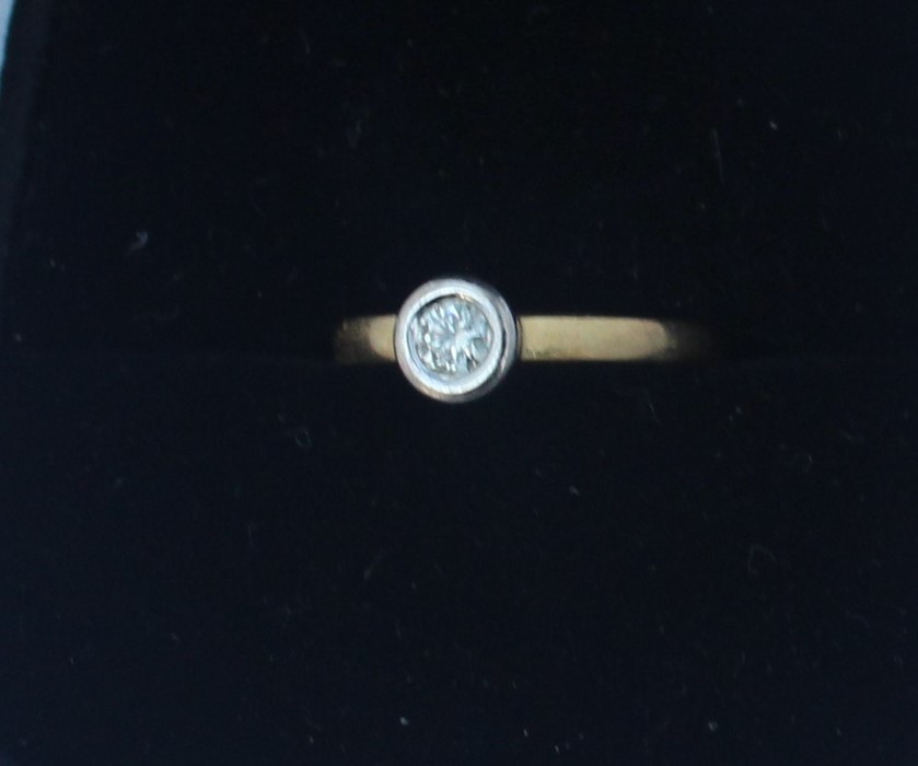 An 18ct. gold and diamond solitaire ring, flush set round cut diamond in white gold, yellow gold