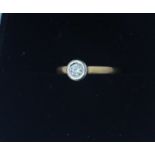 An 18ct. gold and diamond solitaire ring, flush set round cut diamond in white gold, yellow gold