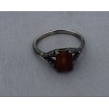 A white metal, brown stone and diamond ring, set rectangular step cut brown stone to centre and