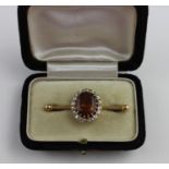 A yellow metal, citrine and diamond brooch, claw set large oval cut citrine within border of