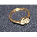 An 18ct. gold and two stone diamond cross-over style ring, set two round old cut diamonds, shank