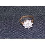 A 9ct. gold and clear stone set cluster ring, having raised stone to centre surrounded by two