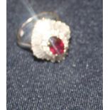 A 14ct. white gold, ruby and diamond cluster ring, the navette mount claw set oval mixed cut ruby to