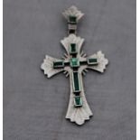 A white gold and emerald crucifix, pierced and with textured face set six square and baguette cut