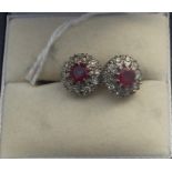 A pair of white precious metal ruby and diamond cluster earrings, set central round cut ruby