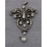 A Belle Epoque precious white metal, diamond and natural pearl pendant, of open work scrolling form,