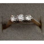 An 18ct. yellow gold and three stone diamond ring, platinum claw set graduated row of three round