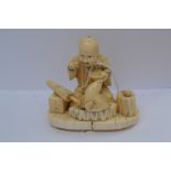 Japanese carved ivory okimono carved as a seated man eating with umbrella in foreground meji