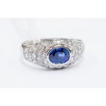 A sapphire and diamond dress ring, set with an oval sapphire, (possibly Ceyon origin) rubover set,