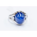 A sapphire and diamond ring, the central cabachon sapphire weighing approx 12 carats, diameter