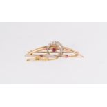 A ruby and diamond crescent brooch, comprising an unmarked yellow metal curved detail, set with