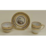 A Derby trio of coffee cup, tea bowl and saucer, each painted with rural landscapes attributed to