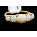 An opal five stone ring, comprising five graduated round cabachon opals, diamond accents set in