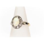 An opal and diamond cluster ring, the oval opal set to the centre approx 8mm x 5.5mm, white opal