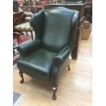 A green leather fireside chair by Sherborne of London, with fire labels